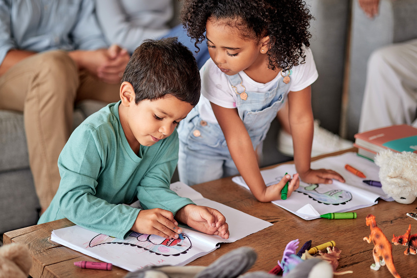 A young boy and girl enjoy coloring dinosaurs with crayons in an activity book in a waiting room